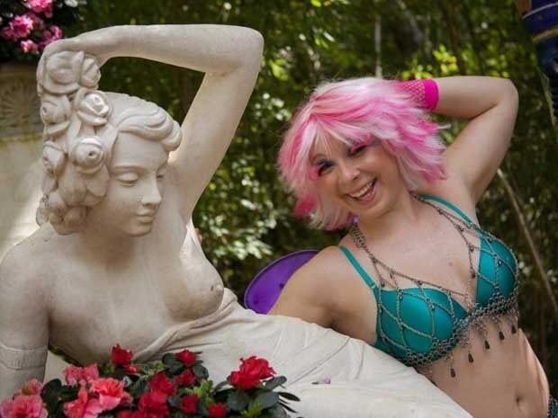 A woman imitating the pose of a statue next to her