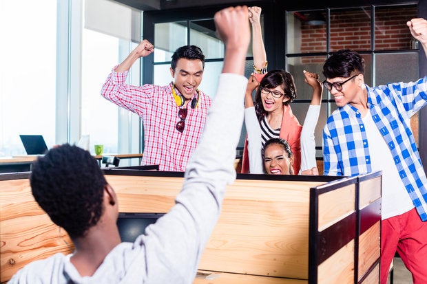 Group of millennials cheering in office