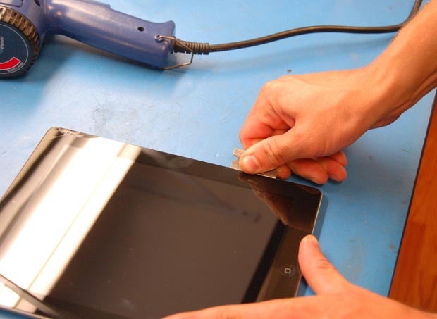 Using a razor blade to cut through the glue that seals the iPad.