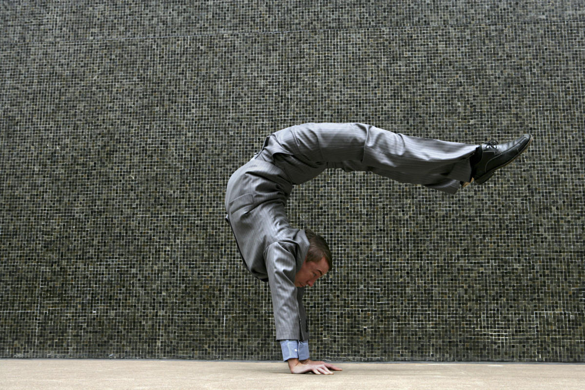 Young businessman doing flexible handstand outdoors twist contort stretch