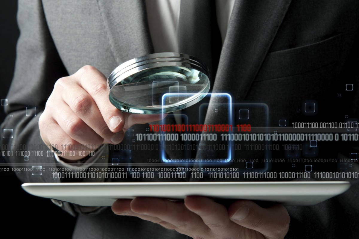 Inspecting a tablet magnifying glass businessman