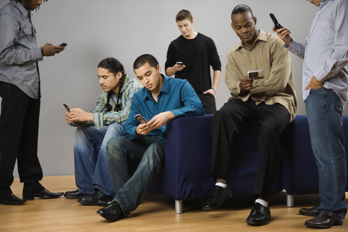 Group of multi-ethnic men text messaging on cell phones 84231223