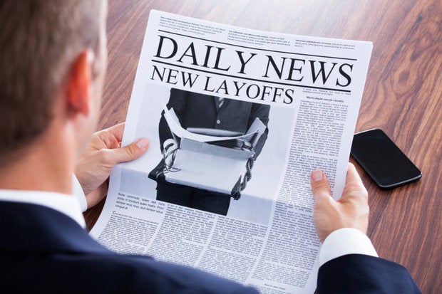 man reading newspaper layoffs jobs