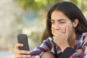 teenager looking at cell phone sextortion stock image