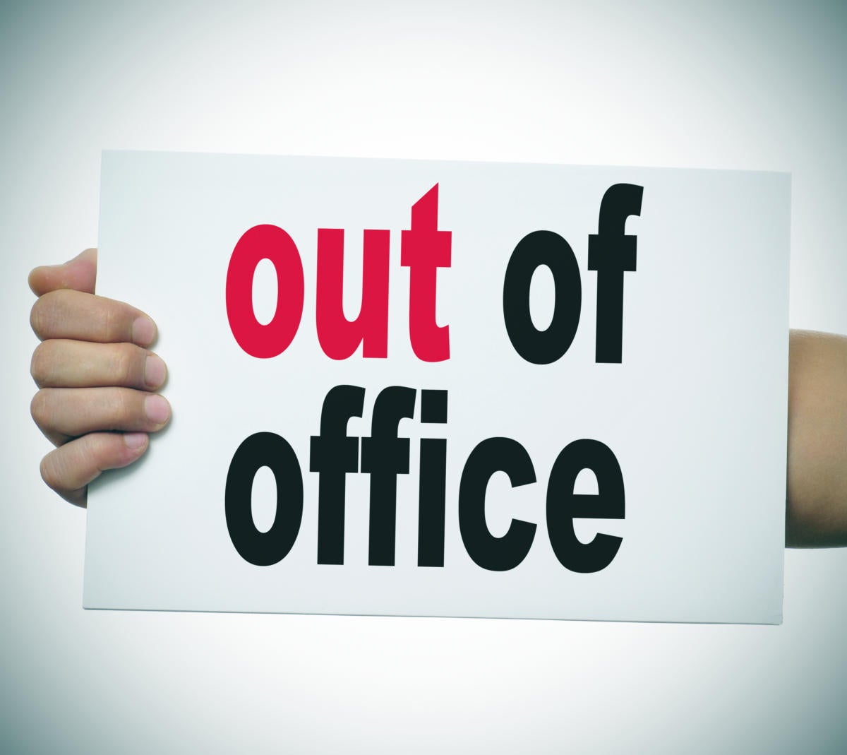 arm holding sign with Out of Office on it