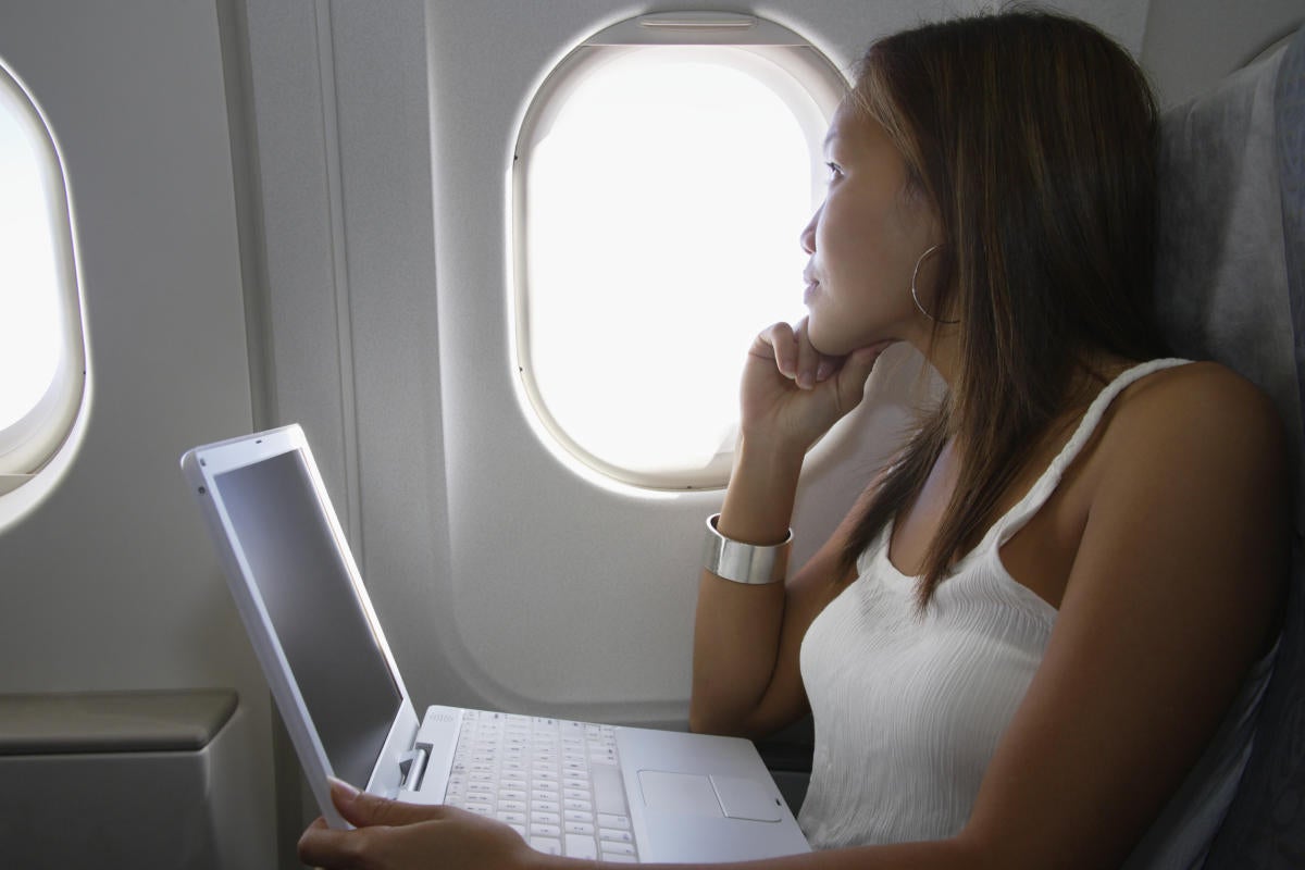 Woman using wi-fi on airplane looking out window
