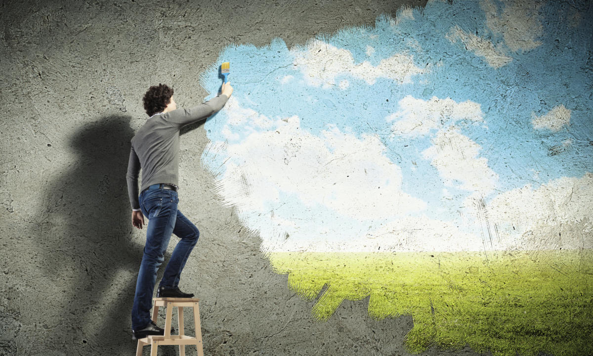 young millennial painting clouds on concrete wall