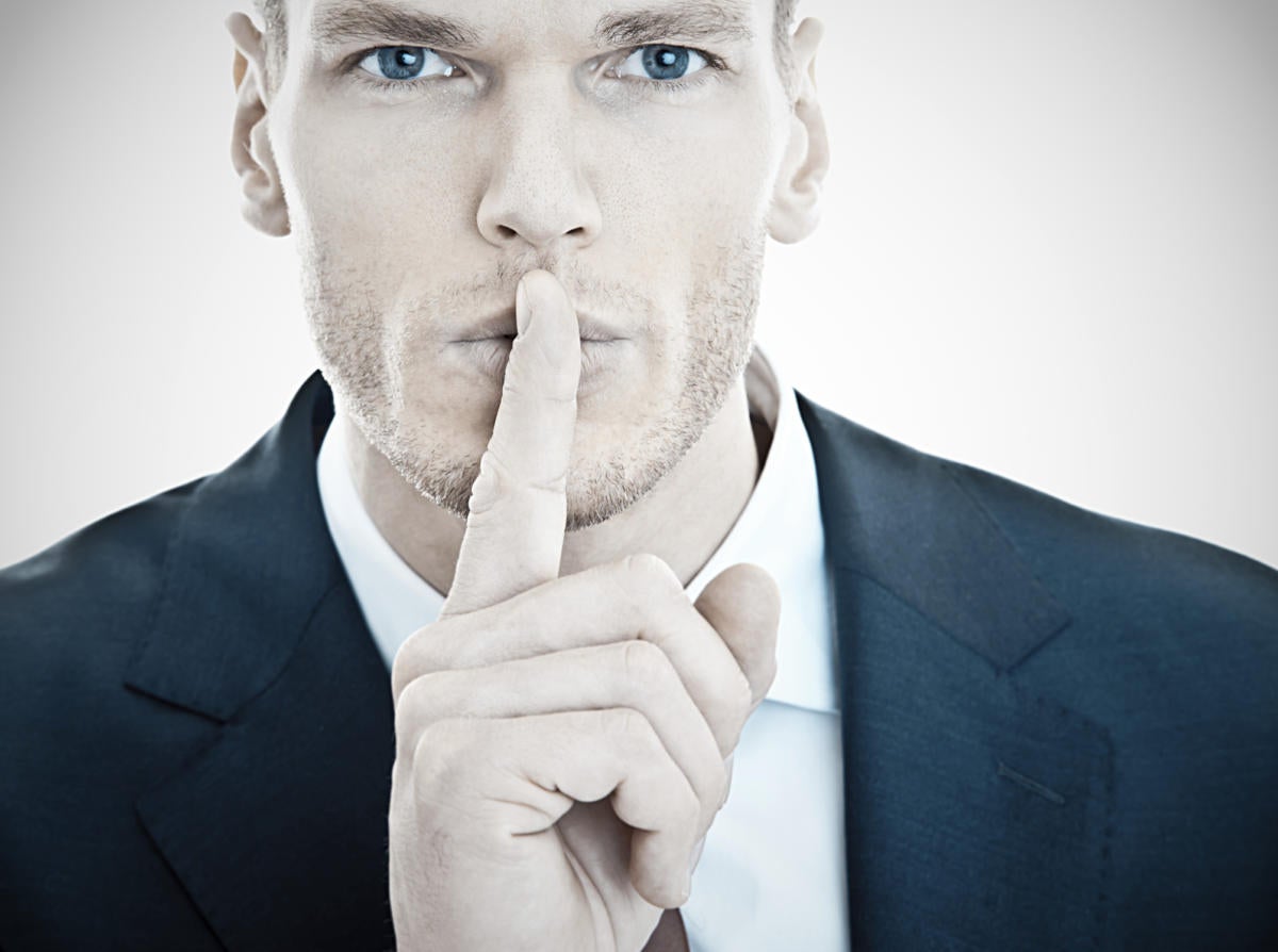 handsome male executive holding finger up to be quiet keep a secret