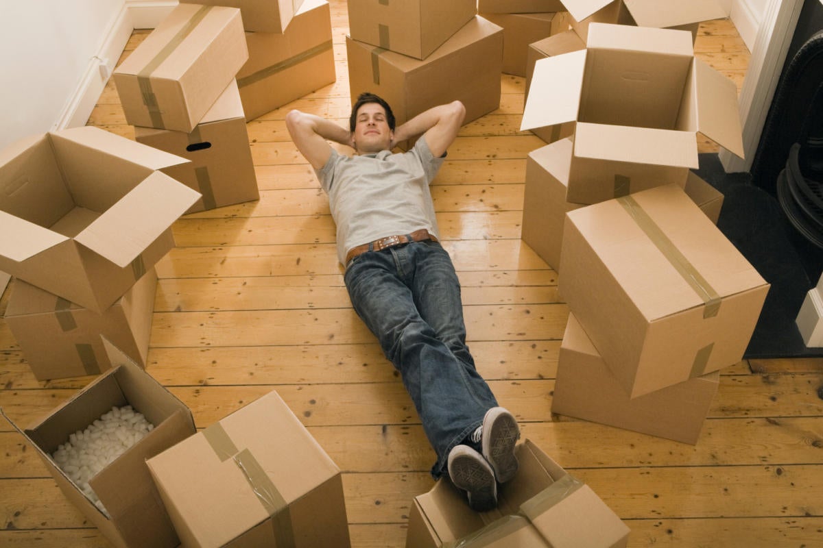 Young man laying on ground surrounded by empty moving boxes