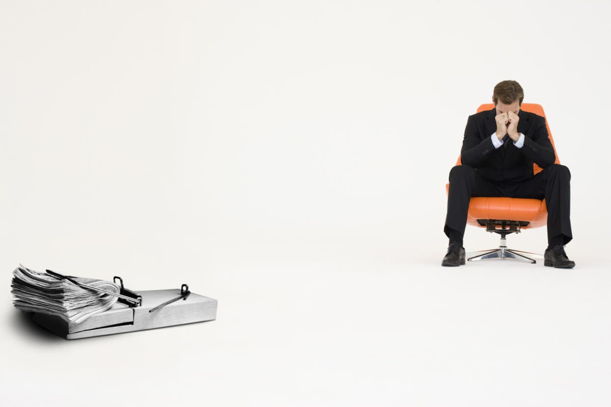 Man looking worn out in mod orange chair with a wad of cash in a mouse trap