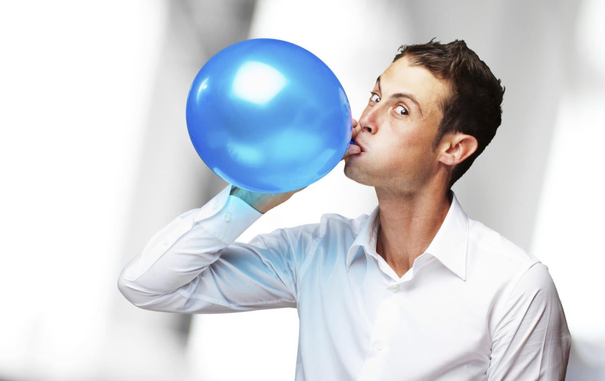 hip young man blowing up blue balloon