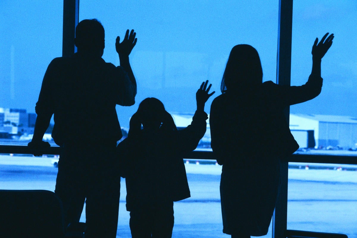 Family in silhouette waving goodbye at airport