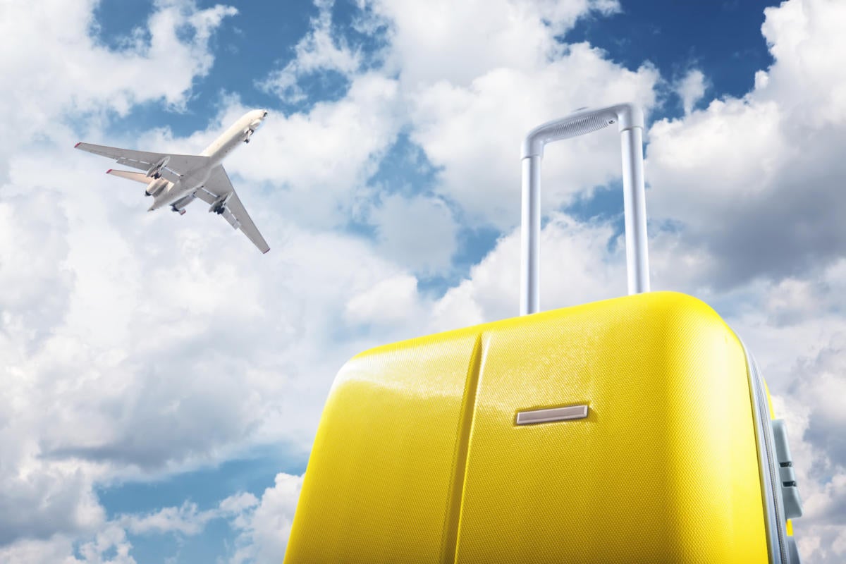 Yellow luggage with airplane and sky