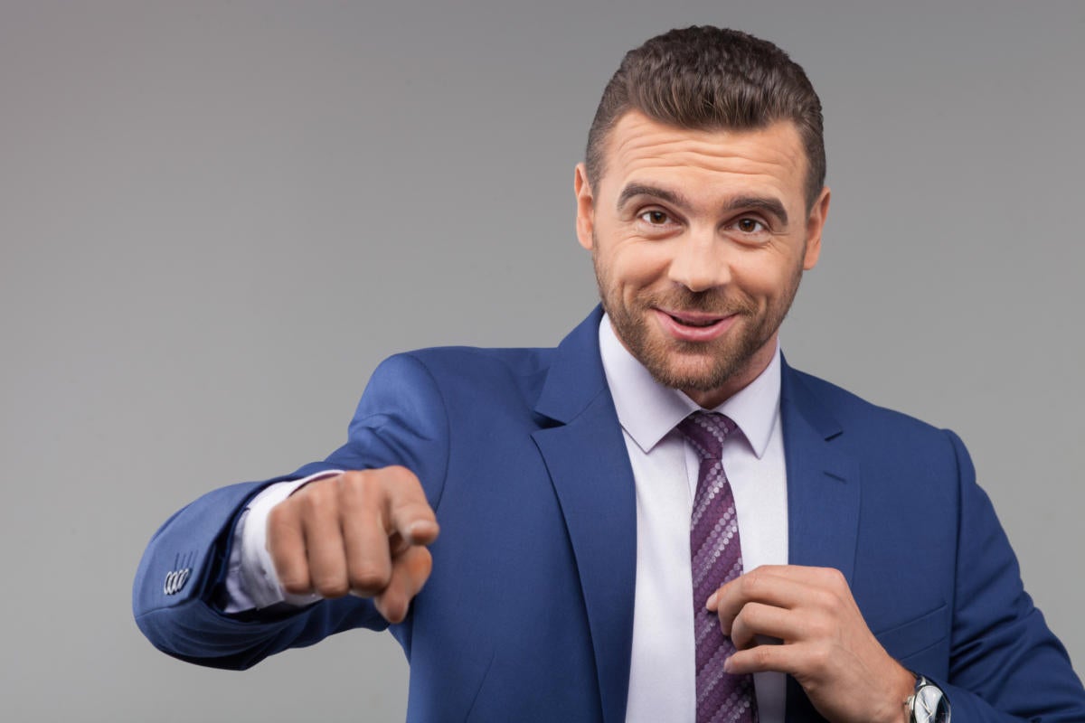 Dapper man in blue suit pointing at camera confidently