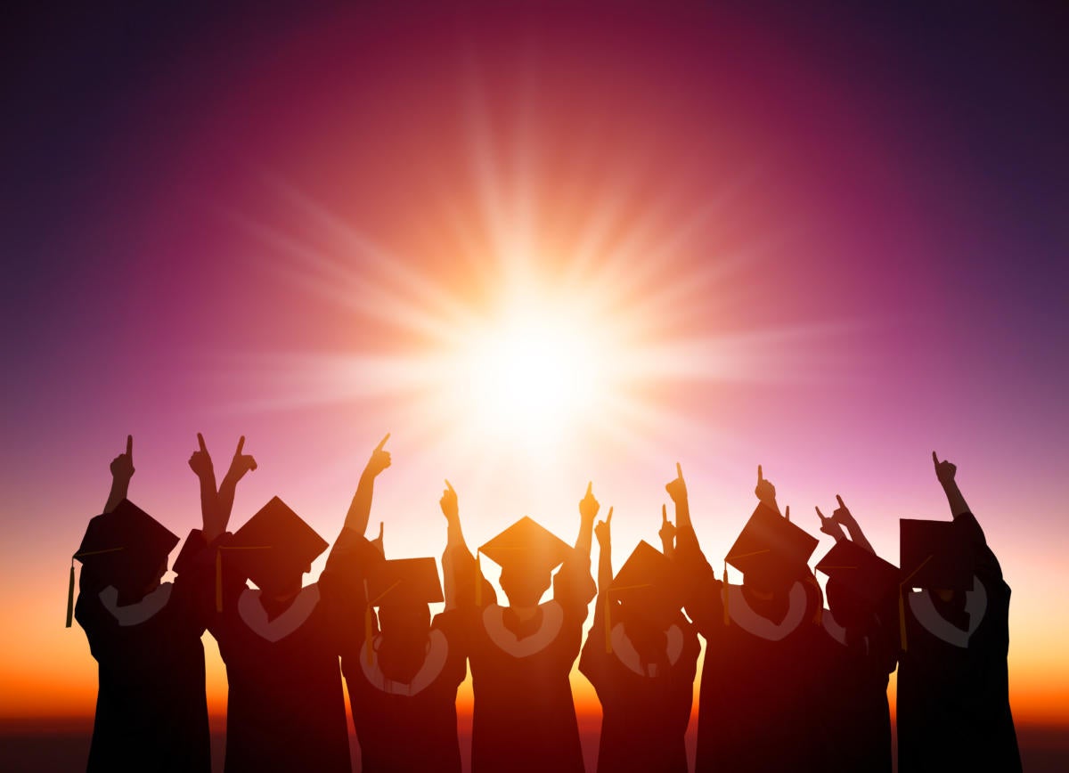 graduates in silhouette with sun setting behind them