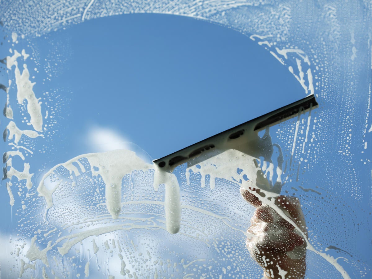 Squeegee cleaning glass with blue sky