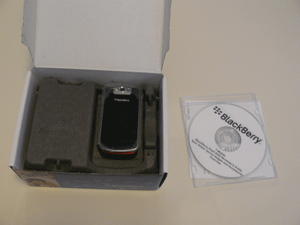 Plastic-wrapped BlackBerry Pearl 8220 Flip in box next to review materials disc