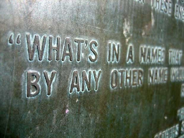 A close up words engraved in a wall. We only see parts of sentences. The first line says What\'s in a name that... Second line says By any other name would...